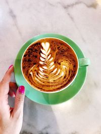 High angle view of woman holding coffee cup on table