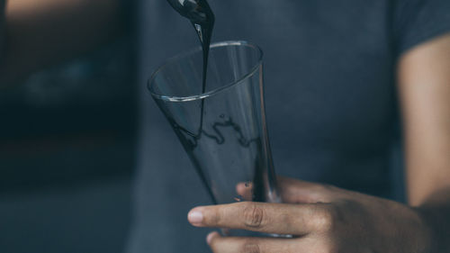 Close-up of hand pouring choco syrup in glass