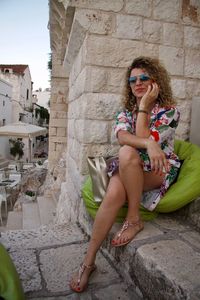 Portrait of smiling young woman sitting on stone wall