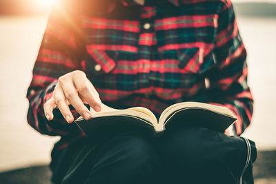 Midsection of man reading book outdoors