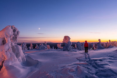 Scenic view of snow covered land against sky during sunset