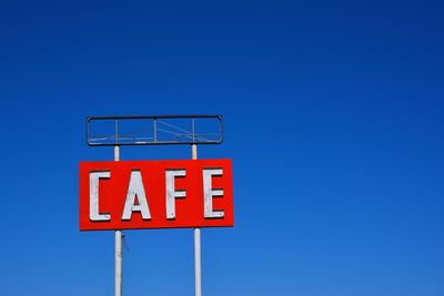 Low angle view of road sign against clear blue sky