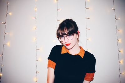 Portrait of young woman standing against wall