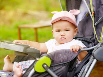 Cute baby girl looking away while sitting in stroller
