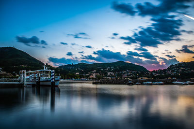 The city of como, in the evening, with the lakefront, the cathedral, and the surrounding mountains.