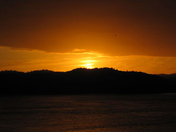 Scenic view of silhouette landscape against orange sky