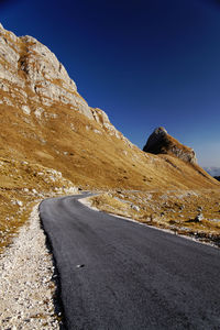 Scenic view of mountain road against clear blue sky