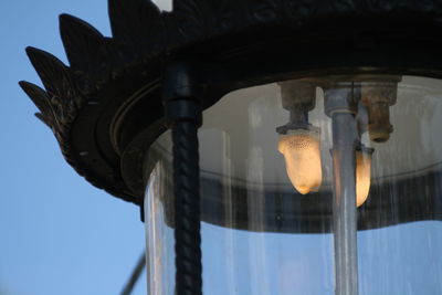 Low angle view of electric lamp by building against sky