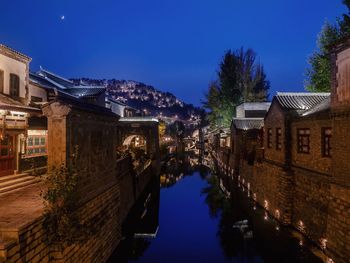 Canal amidst buildings against blue sky at night