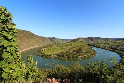 Scenic view of landscape and lake against clear blue sky