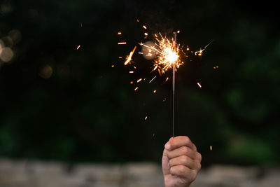 Child hand holding a burning sparkler firecracker at celebration
