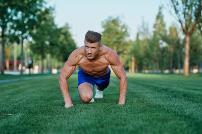 Portrait of young man exercising on field