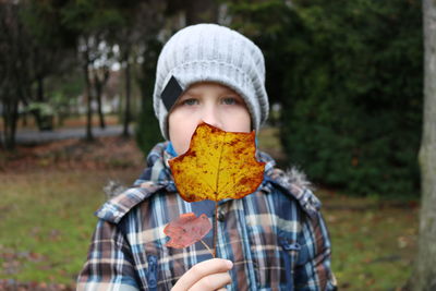 Portrait of girl holding autumn leaf at yard