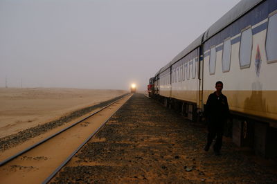 Man standing on railroad track against sky at night