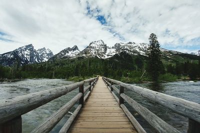 Footbridge over lake against sky during winter