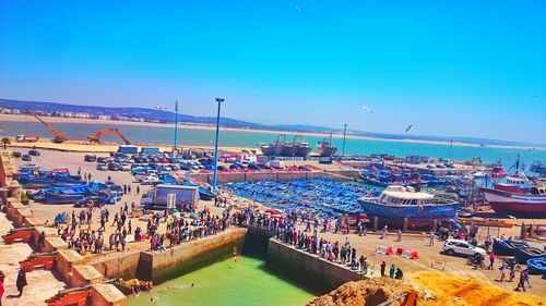 People relaxing on beach against blue sky