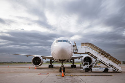 Airplane on airport runway against sky