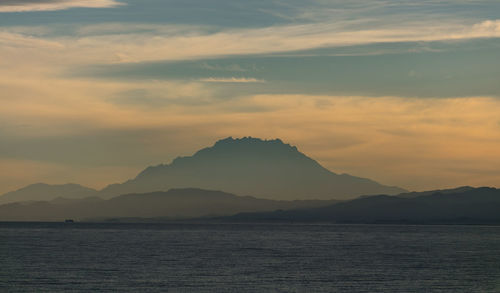A silhouette of a mount kinabalu from afar during sunrise with a morning mist 