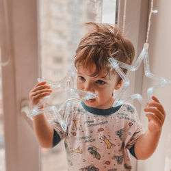 Cute boy holding star shape at home