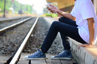 Man using mobile phone while sitting on railroad track