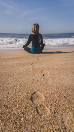 Rear view of woman sitting on beach