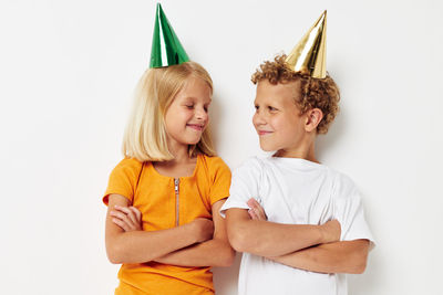 Sibling wearing party hat against white background