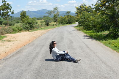 Full length of young woman sitting on road