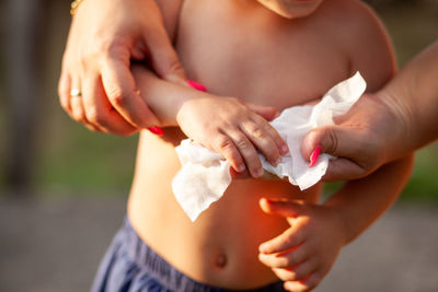 Cropped hand of mother wiping son 