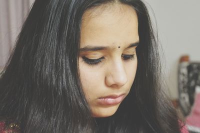 Close-up of teenage girl with black hair at home