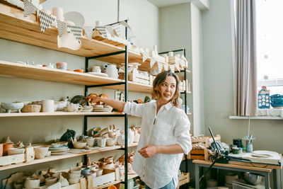A woman head of pottery workshop near shelves with products