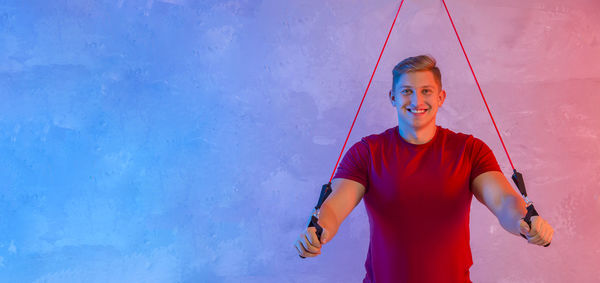 Portrait of young man exercising against wall