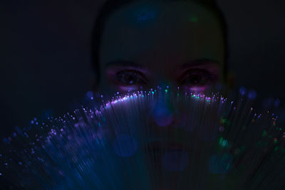 Close-up portrait of young man against illuminated lights