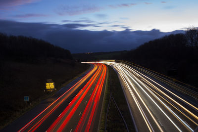 High angle view of light trails on two lane highway at dusk