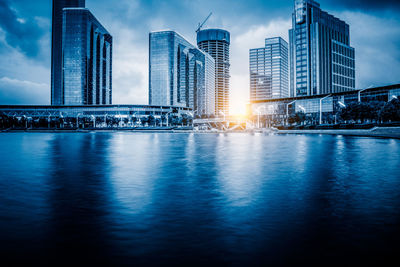 Illuminated buildings in city against sky at dusk