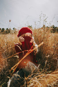 Beautiful woman covering face while sitting amidst plants