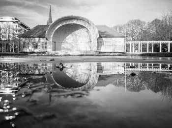 Reflection of arch bridge in lake against sky