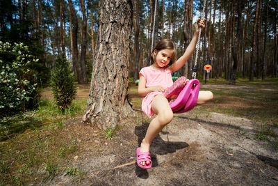 Happy woman sitting on pink tree