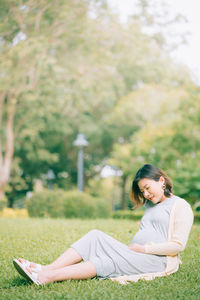 Pregnant woman sitting on grass at park