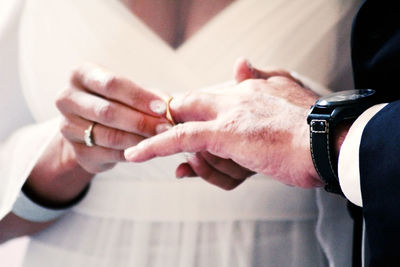 Midsection of couple exchanging wedding rings
