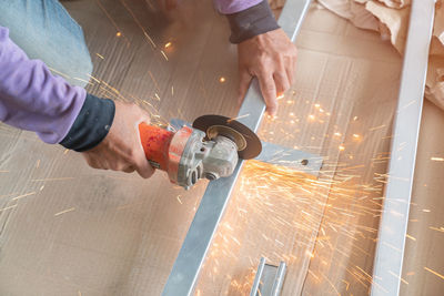 Worker cutting metal with electric grinder in construction site.