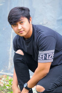 Portrait of young man sitting on field