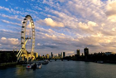 Ferris wheel in city against cloudy sky