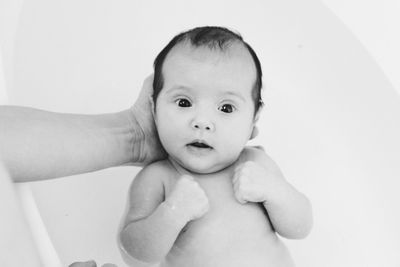 High angle view of person holding baby girl over bathtub