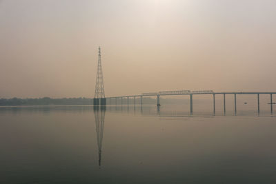 Bridge over water against sky during sunset