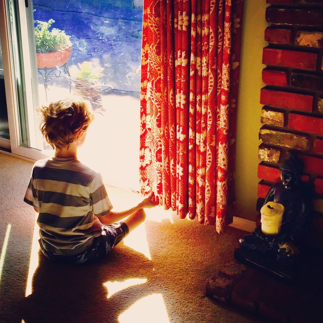 REAR VIEW OF BOY SITTING ON SHELF