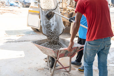 Workers load cement from trucks onto carts to pour the floor in areas that trucks can't reach.