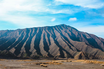 Scenic view of mountain range against cloudy sky