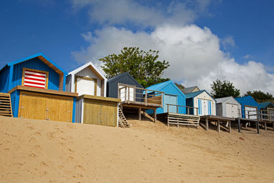 Huts on beach against blue sky