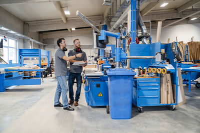 Two male carpenters talking in production hall