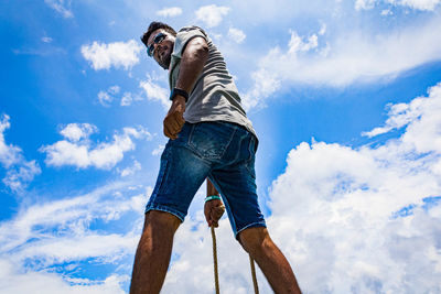 Low angle view of man standing against cloudy sky